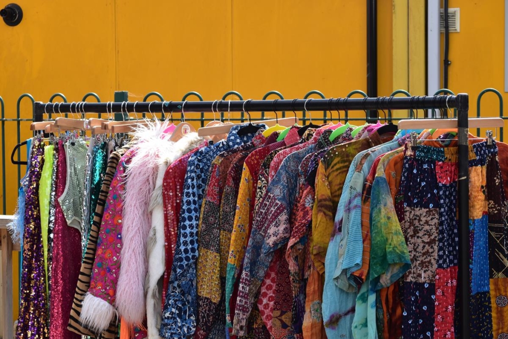 Rail of brightly coloured, decorated clothes on a rail at a market stall.