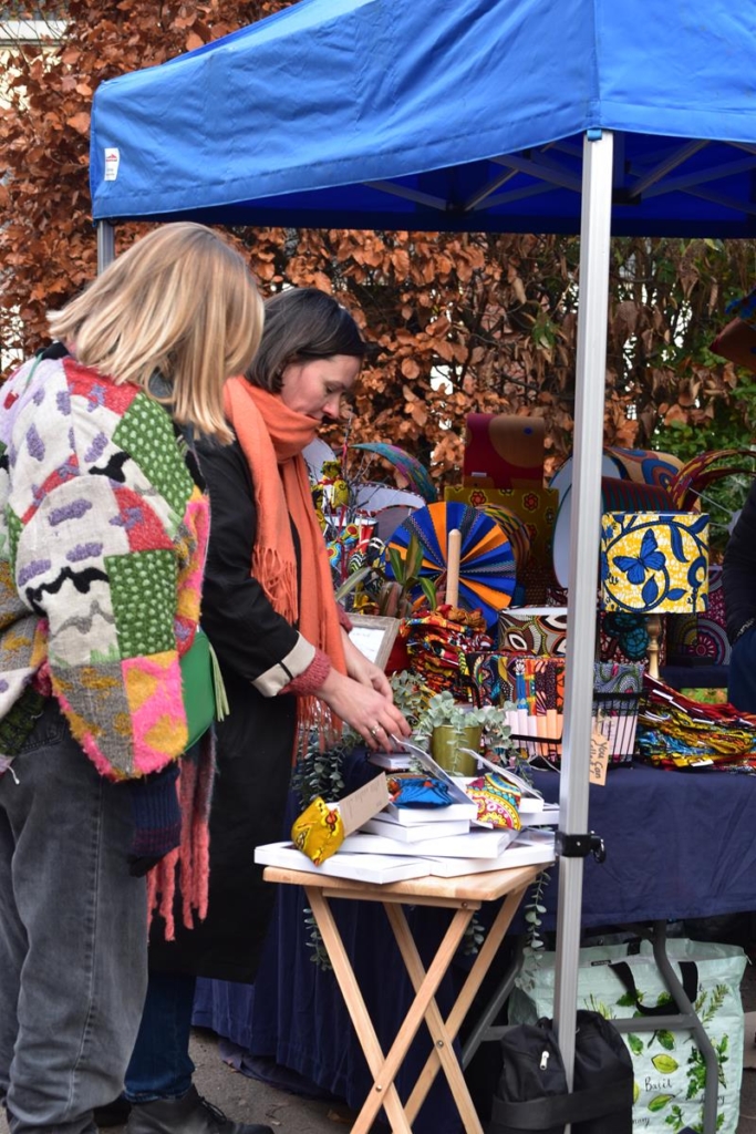 Shoppers at a Christmas market, wearing brightly coloured winter clothes.