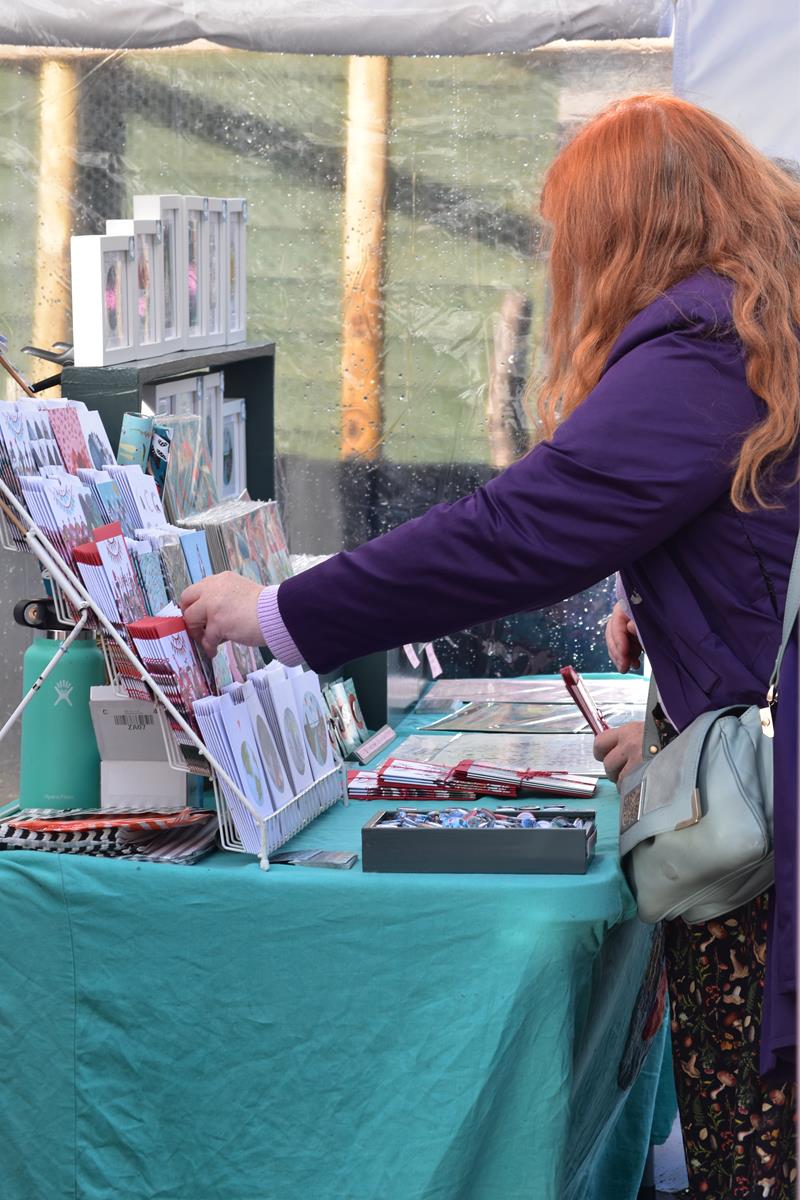 Shoppers browsing Christmas cards at a winter market.